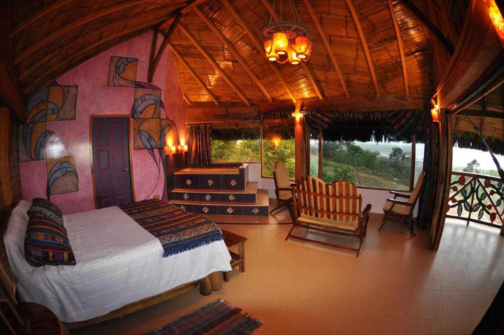 een slaapkamer met een bed en stoelen in een kamer bij Azuluna Ecolodge in Puerto López