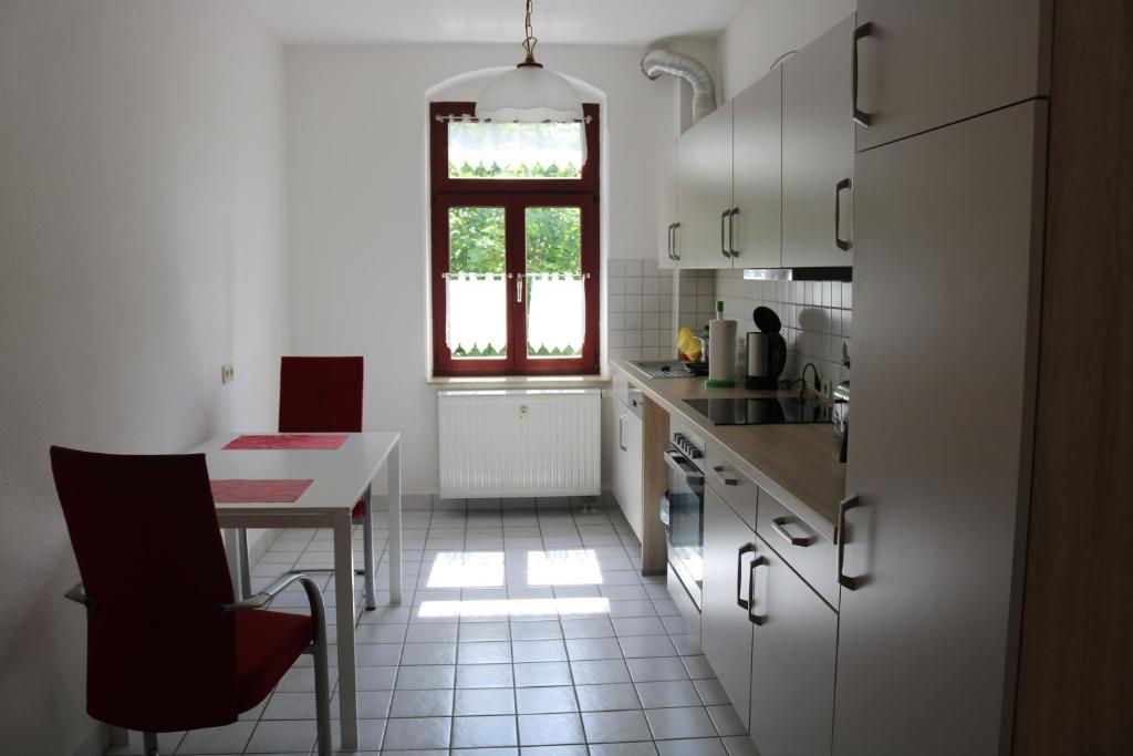 cocina blanca con mesa y ventana en Ferienwohnung Post, en Ottendorf-Okrilla