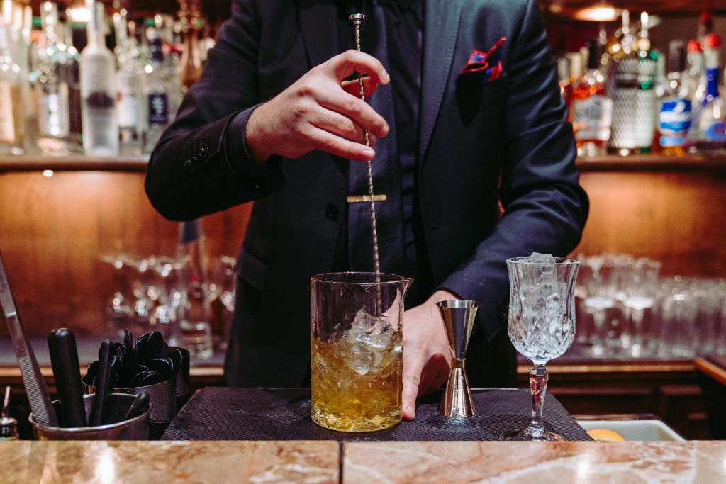 a man is making a drink at a bar at Hotel Metropole Venezia in Venice