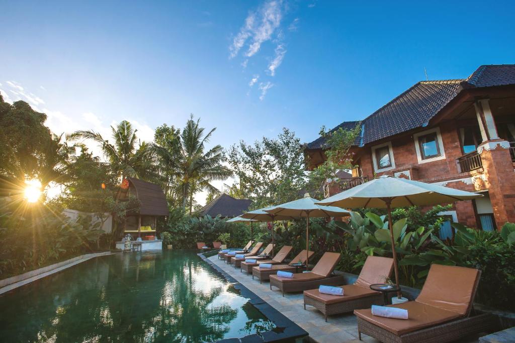 - une piscine avec des chaises et des parasols à côté d'un bâtiment dans l'établissement Rama Phala Resort & Spa, à Ubud
