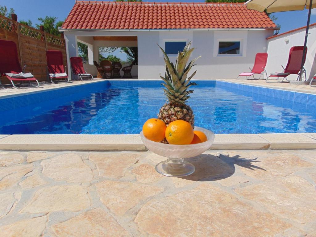 a bowl of fruit sitting next to a swimming pool at Holiday Home Donji Lepuri in Lisičići