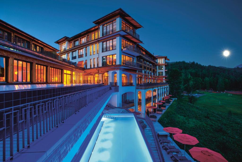 a large building with a swimming pool in front of it at Schloss Elmau Luxury Spa Retreat & Cultural Hideaway in Elmau