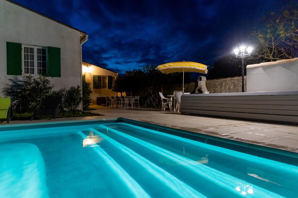 a swimming pool in front of a house at night at Villa des Jaulaines, Villa en bord de mer - Ile de Ré in Sainte-Marie-de-Ré