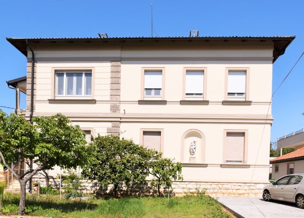 ein weißes Haus mit einem Baum davor in der Unterkunft Vila Siega in Zadar