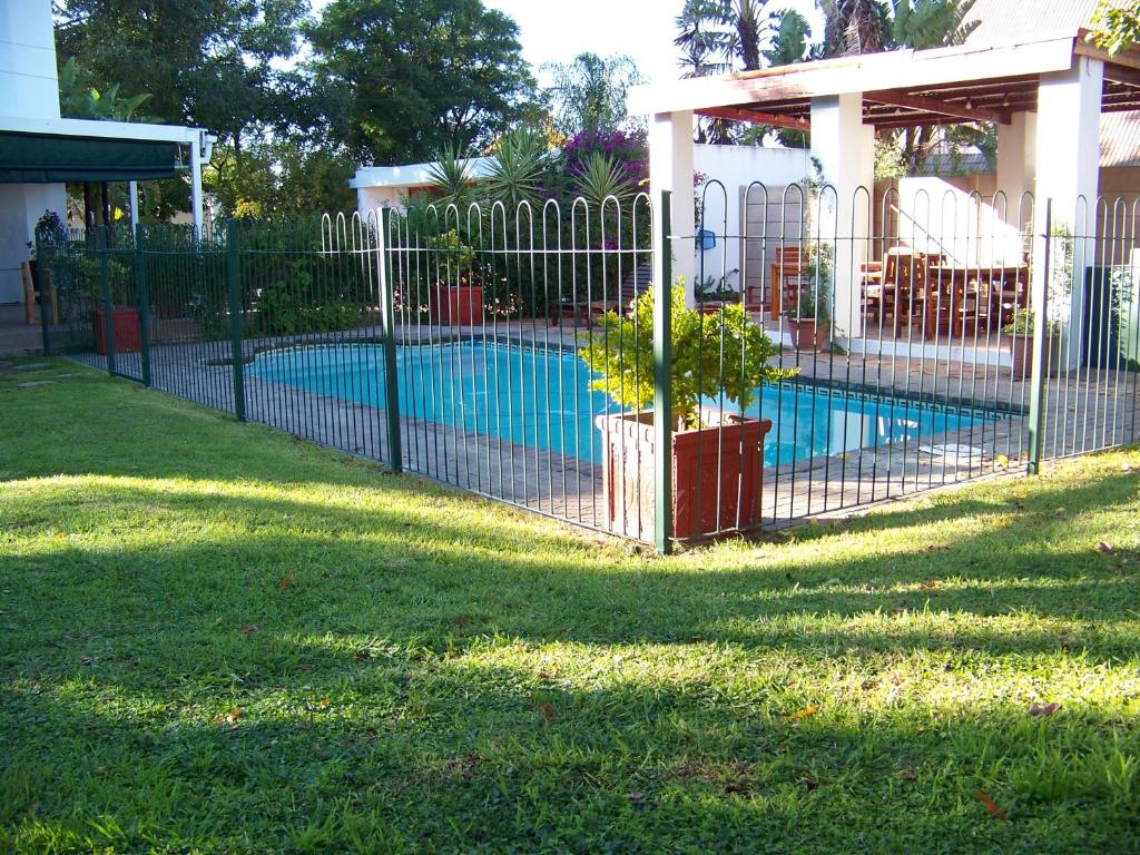 a fence in front of a swimming pool at Haus Victoria Self Catering Cottages in Oudtshoorn