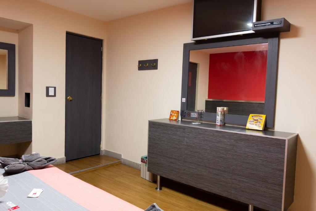 A compact bedroom corner with a dark dresser, mirror, and wall-mounted television.