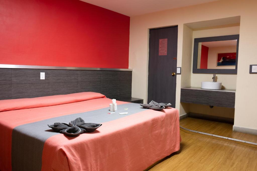 A bedroom with two beds uses bright coral bedding and a red accent wall.
