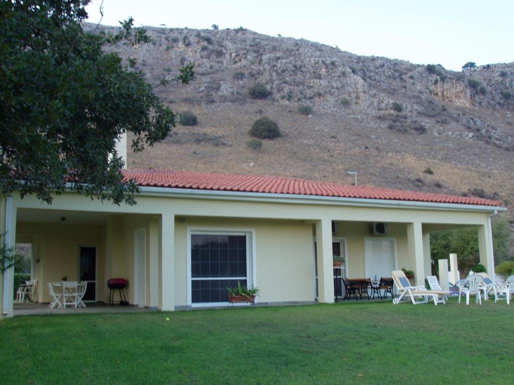 una casa con sillas y una montaña en el fondo en Kalogria West Peloponnese "VILLA ΜΑΝOLIA ", en Áraxos