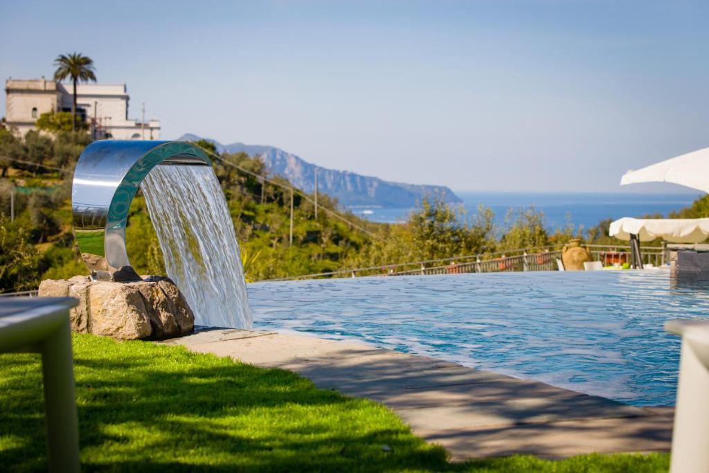 une piscine avec une fontaine dans l'herbe dans l'établissement Oleum, à Massa Lubrense