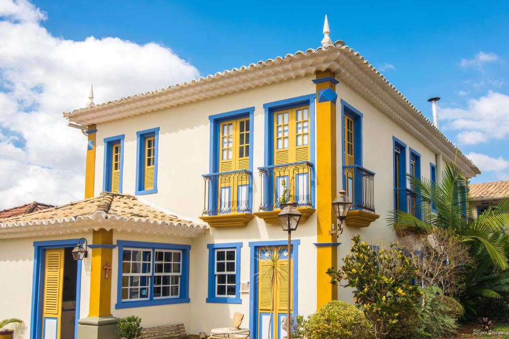 Casa amarilla y azul con ventanas azules en Arraial Velho Pousada Tematica, en Tiradentes