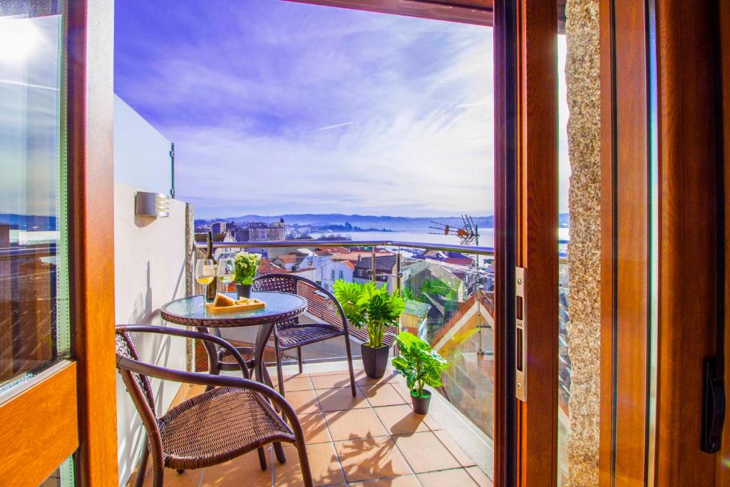 balcón con mesa, sillas y vistas en Casa do Outeiro, en Cangas de Morrazo