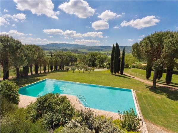 a swimming pool in the middle of a field with trees at Cortile Del Pozzo in Buonconvento