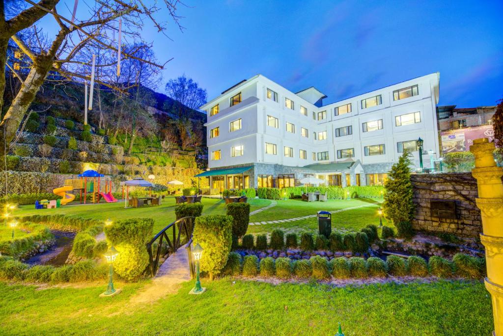 a large white building with a garden in front of it at The Rock Manali Centrally Heated Property in Manāli