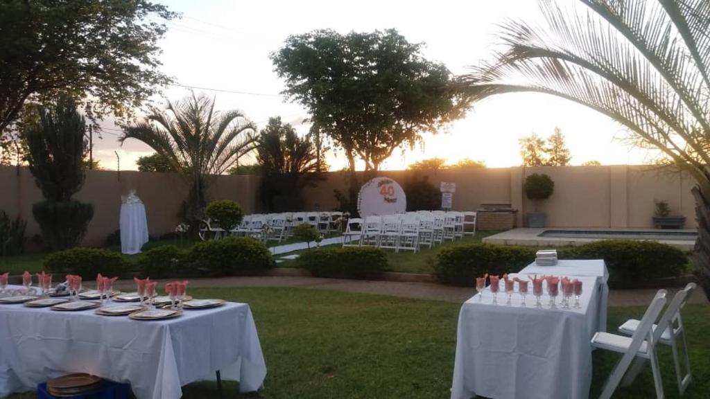 a table with white table cloths and chairs in a yard at Fahms in Letlhakane