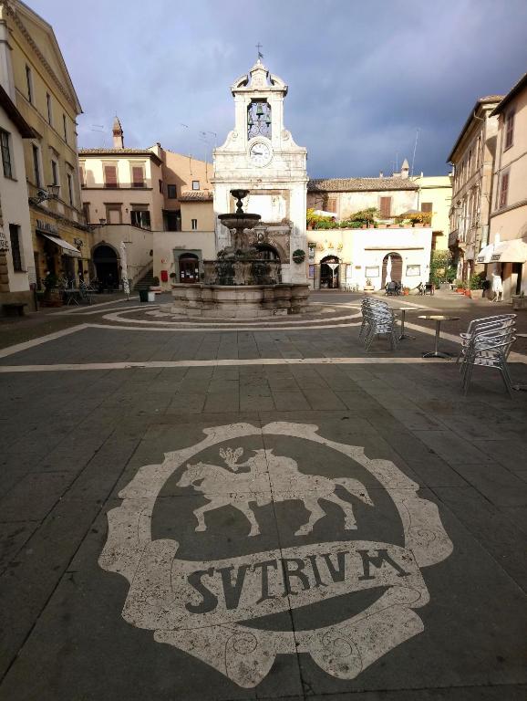 a square with a fountain and a clock tower at Nerone's - Sutri Bed & Dinner in Sutri