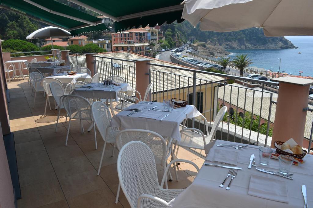 un restaurante con mesas y sillas con vistas al océano en Hotel Delle Rose, en Bonassola