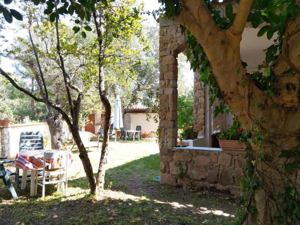 un bâtiment en pierre avec une table et un arbre dans l'établissement Pedras House Holidays, à Santa Maria Navarrese