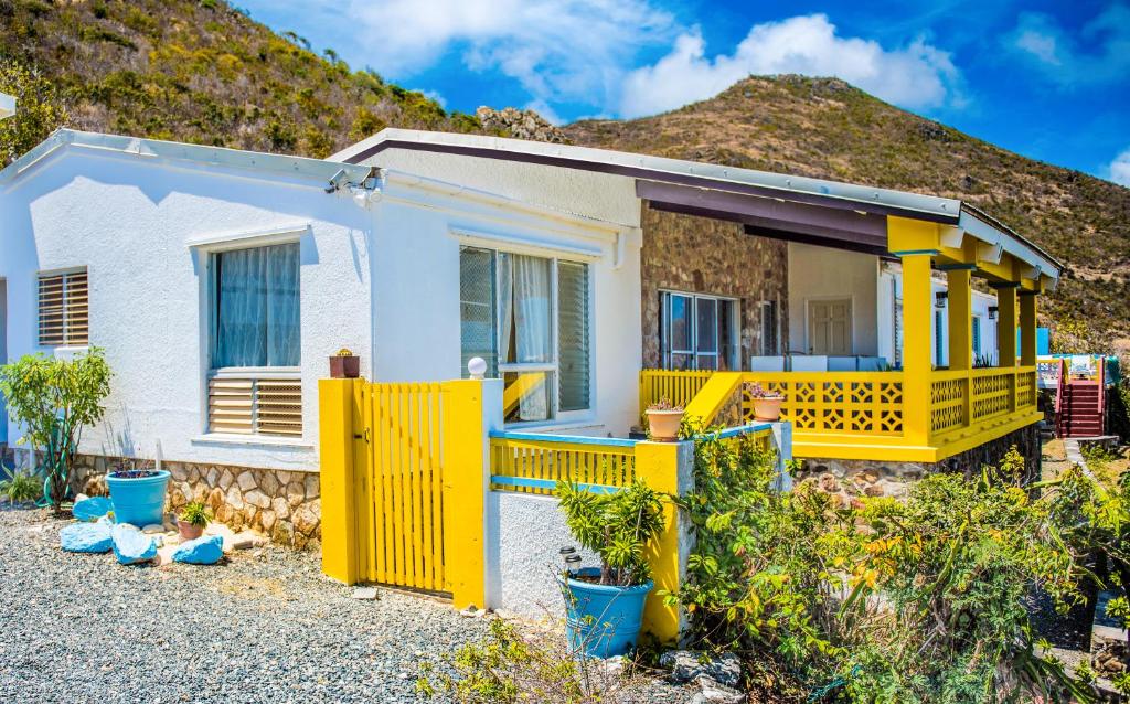 a yellow house with a mountain in the background at Villa Fleur De Mer Sint Maarten in Upper Prince's Quarter