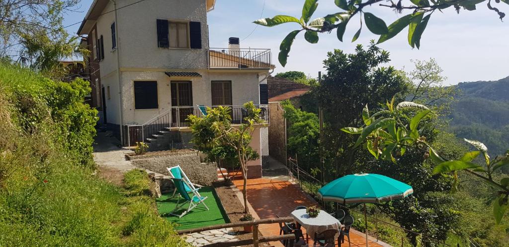 a house with an umbrella and a table and chairs at Il Villino in San Colombano Certenoli