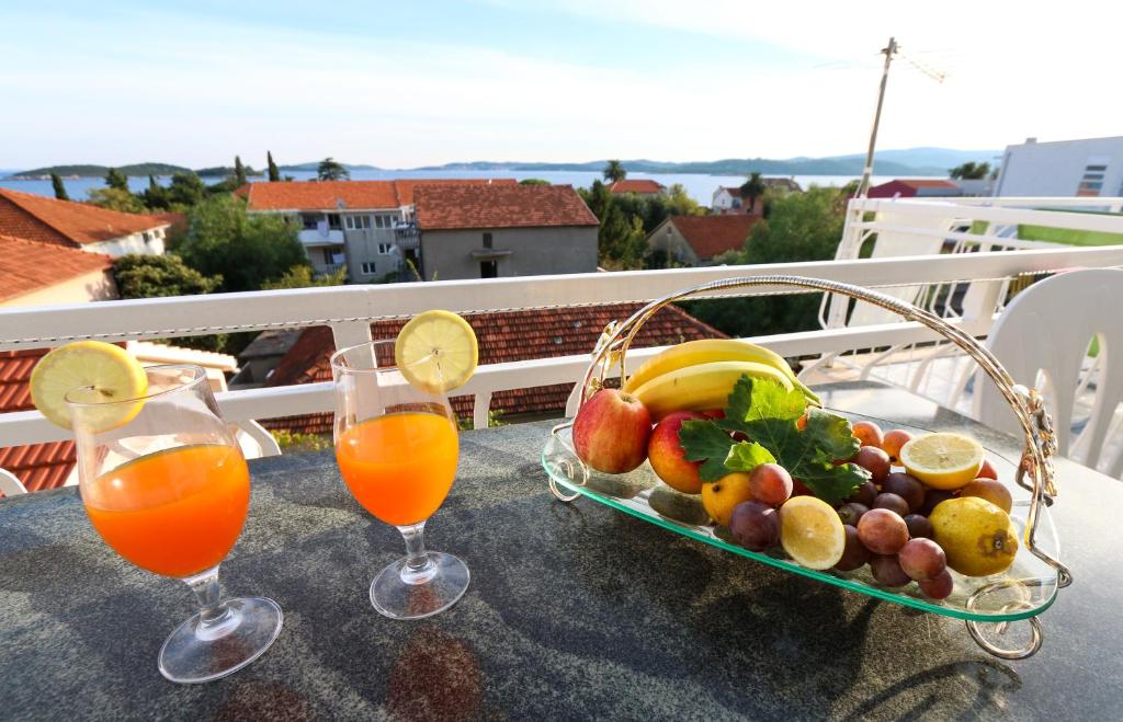 a bowl of fruit on a table with two glasses of juice at Apartmani Pavla in Orebić
