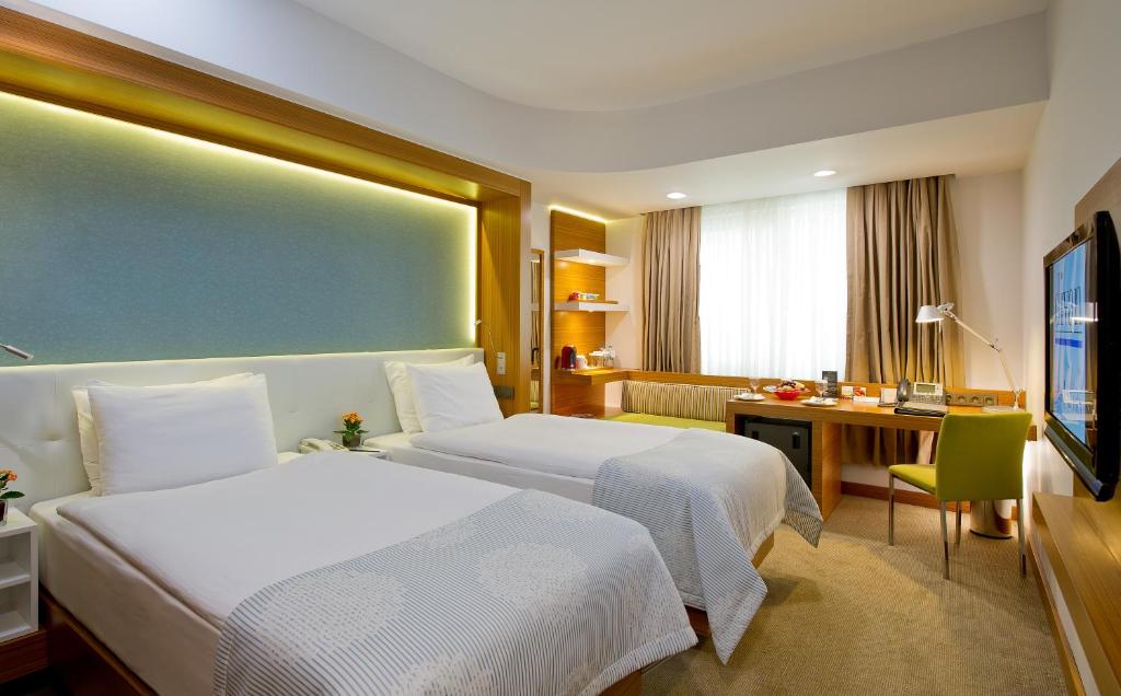 a hotel room with two beds and a desk at Divan Istanbul City in Istanbul