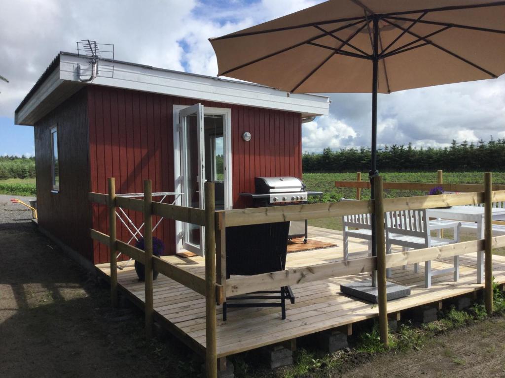 een tiny house met een paraplu en een grill bij Feriehytten Hønsehuset in Løkken