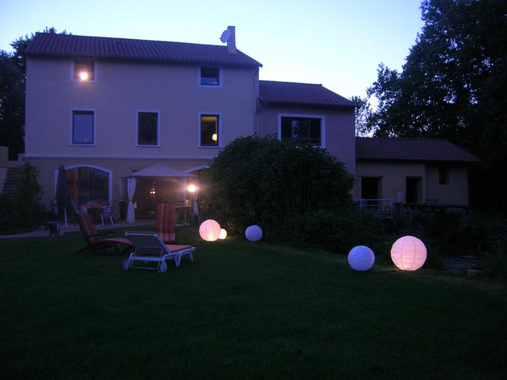 a house with lit spheres in the yard at night at La Chambre du Meunier in Laiz
