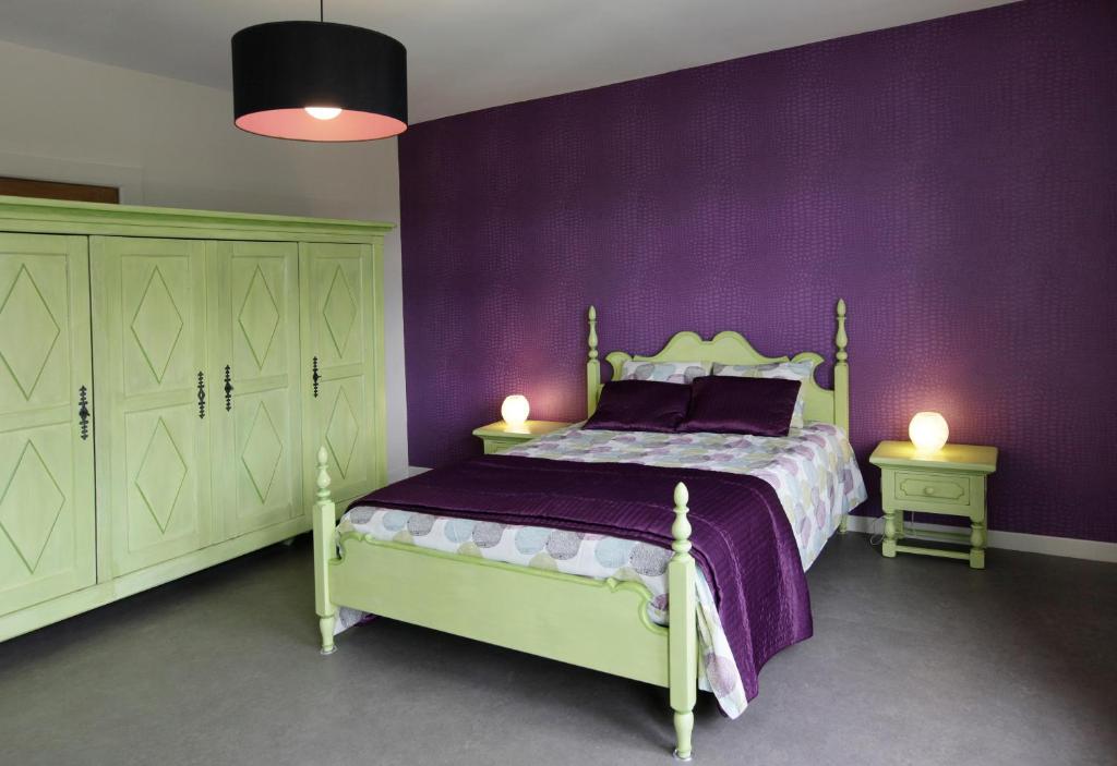 1 dormitorio con paredes moradas y 1 cama con 2 lámparas en Aux Herbes Folles, en Herve