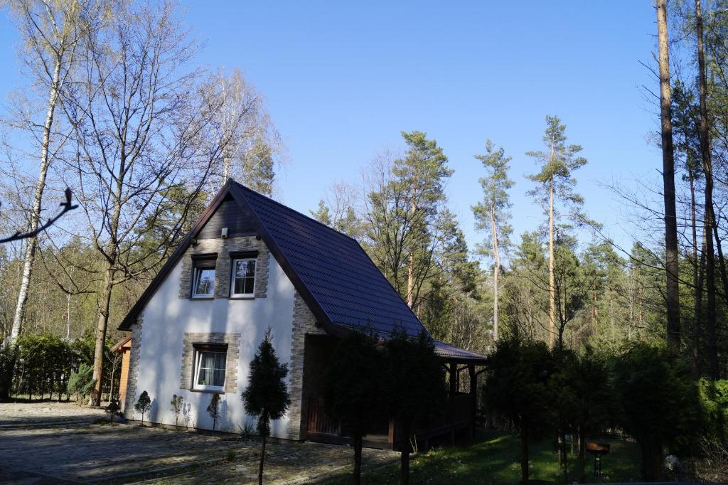 una pequeña casa blanca con techo negro en Uroczy domek do wynajęcia w Bogaczewie nad jeziorem Narie, en Morąg