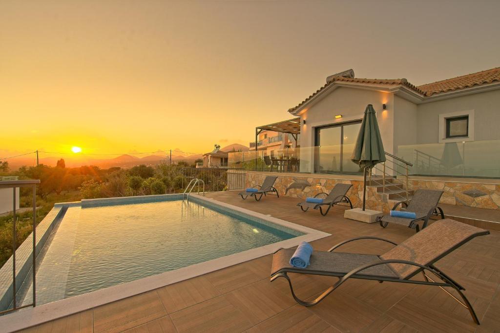 a villa with a swimming pool and a sunset at Vista Blu Villa in Vlachata