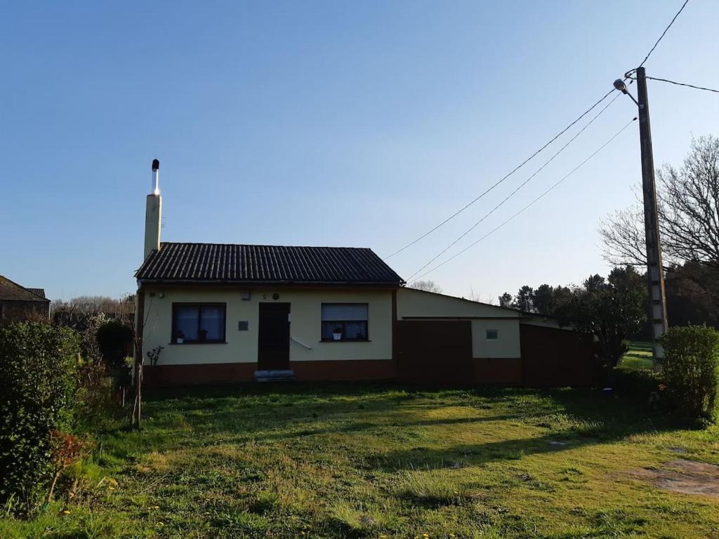 una casa blanca con un techo negro en un campo en La casa del tio Antonio, en Taboy