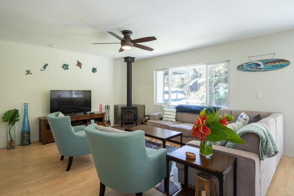 a living room with a couch and chairs and a tv at Mauna Ua in Volcano