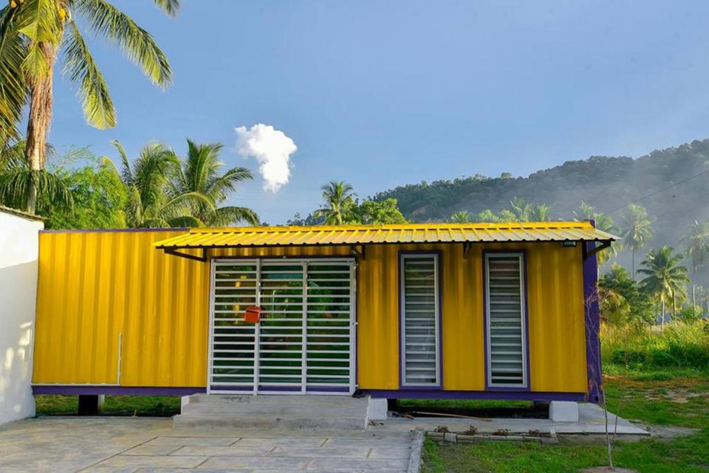 een geel huis met een geel dak op een veld bij Yellow Cube at Lumut Cube Homestay Kontena in Lumut