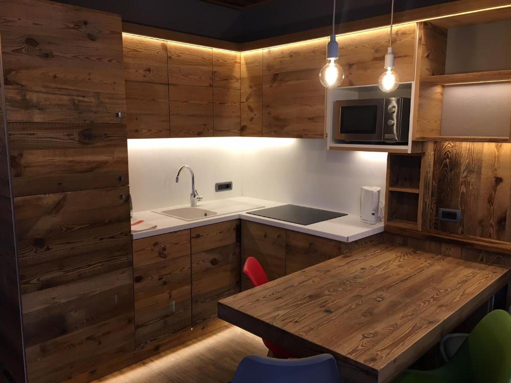 リヴィーニョにあるSki Holidays Apartmentsの木製の壁と木製テーブル付きのキッチン