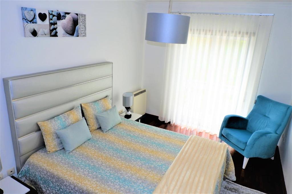 ein Schlafzimmer mit einem Bett und einem blauen Stuhl in der Unterkunft Estrelinha GuestHouse in Nazaré