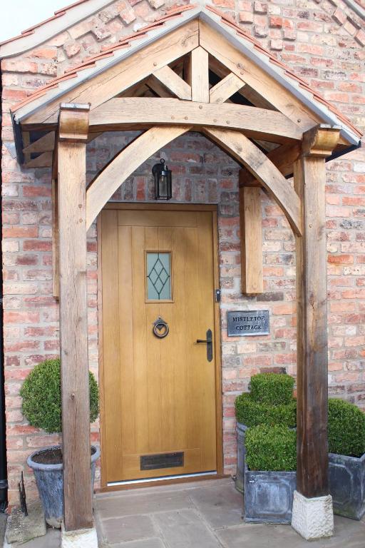 einen hölzernen Eingang zu einem Backsteingebäude mit einer Holztür in der Unterkunft Mistletoe Cottage in York