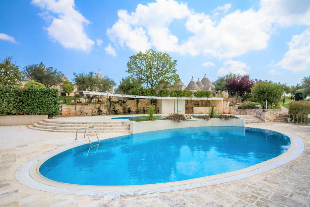 a swimming pool in a yard with a patio and trees at Il Palmento Hotel Relais in Locorotondo