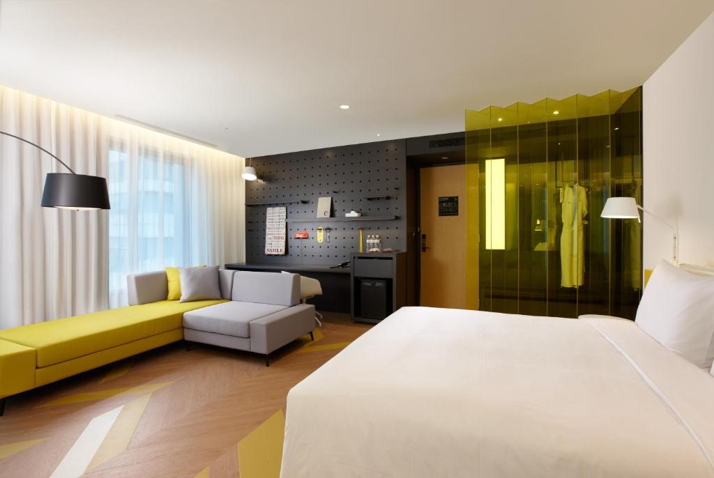 a bedroom with a white bed and a yellow couch at The Place Taipei in Taipei