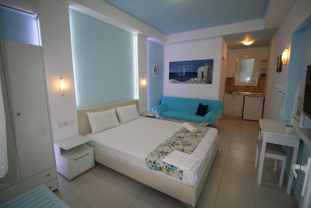a bedroom with a white bed and a blue couch at Alexandros Studios in Asprovalta