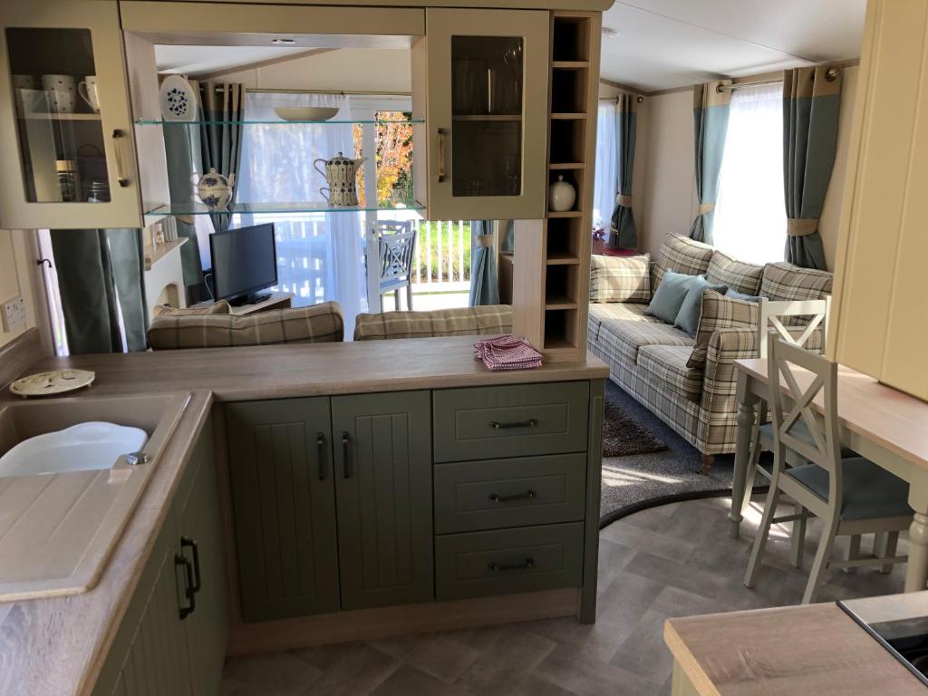 a kitchen and living room with a couch at Deluxe Riverside Static Caravan in Cheddar