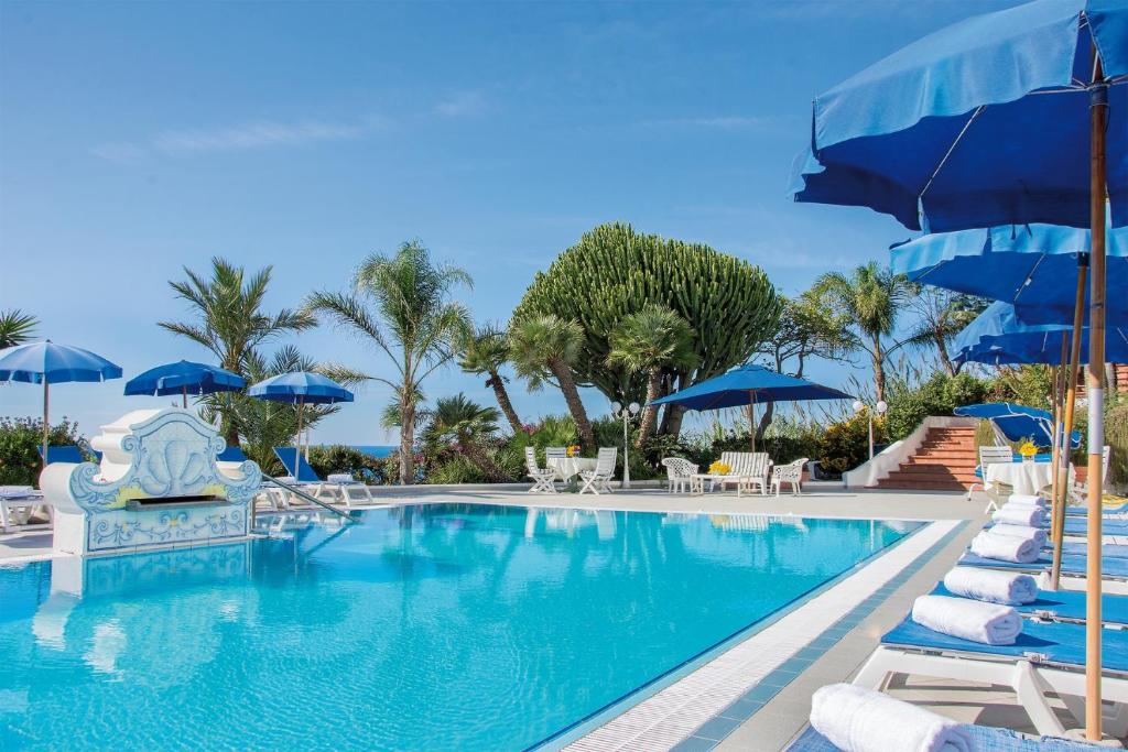 a swimming pool with chairs and umbrellas at Hotel Capizzo in Ischia