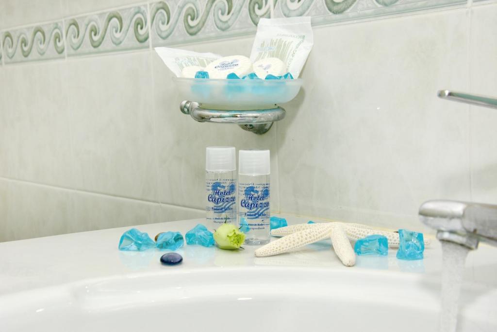 a bathroom counter with a sink and a bowl of toiletries at Hotel Capizzo in Ischia
