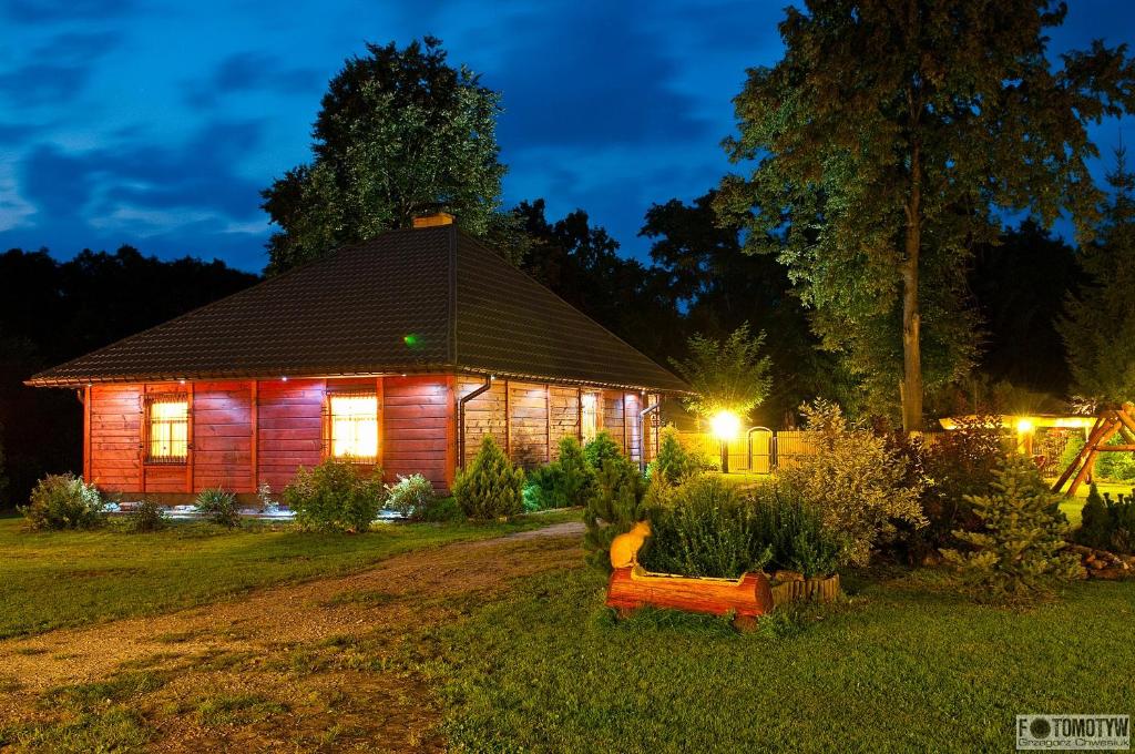 a wooden house with a bench in the yard at night at Gajówka Sajczyce - gospodarstwo agroturystyczne in Chełm