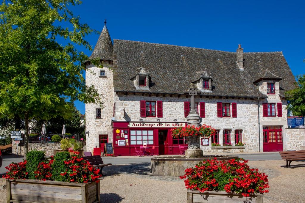 ein Gebäude mit roten Fensterläden und Blumen davor in der Unterkunft Logis Hôtel Restaurant Auberge de la Tour in Marcolès