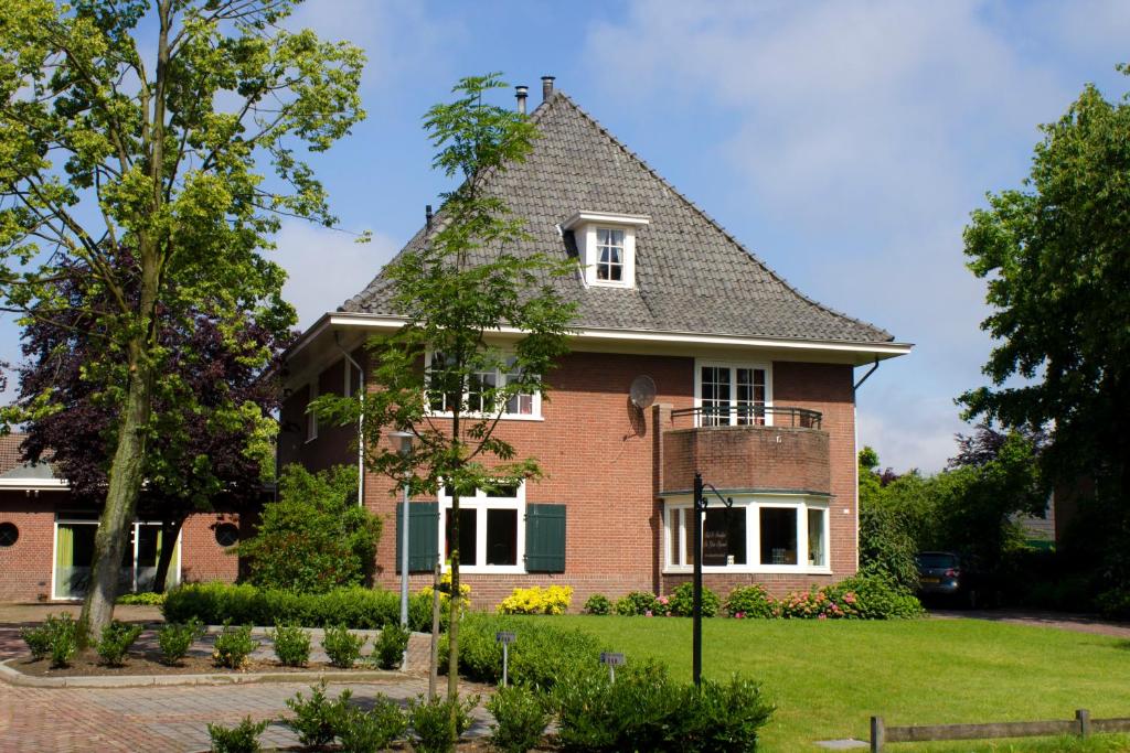 une grande maison en briques avec un toit en gambrel dans l'établissement Bed and Breakfast De Grote Byvanck, à Westervoort