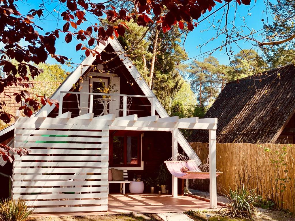 una casa de juegos blanca con una silla rosa delante en Nadi's Holiday Home – Heart of Woods, Szentendre Island, en Szigetmonostor