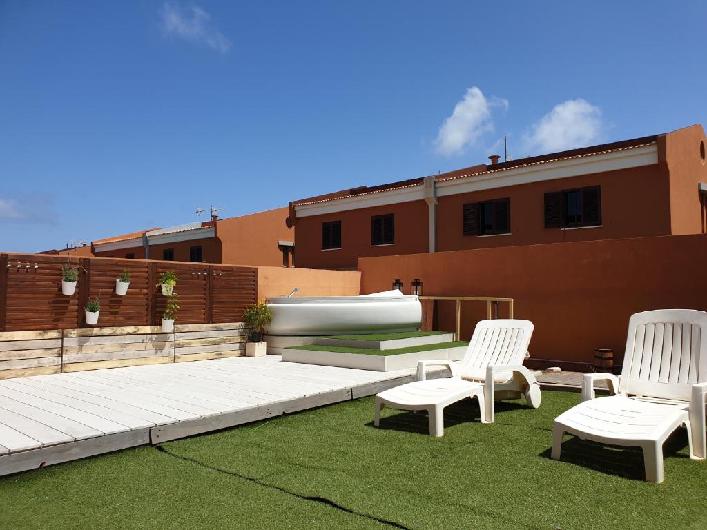 un patio con sillas blancas y una piscina en la azotea en La Casa Sahi, en Gáldar