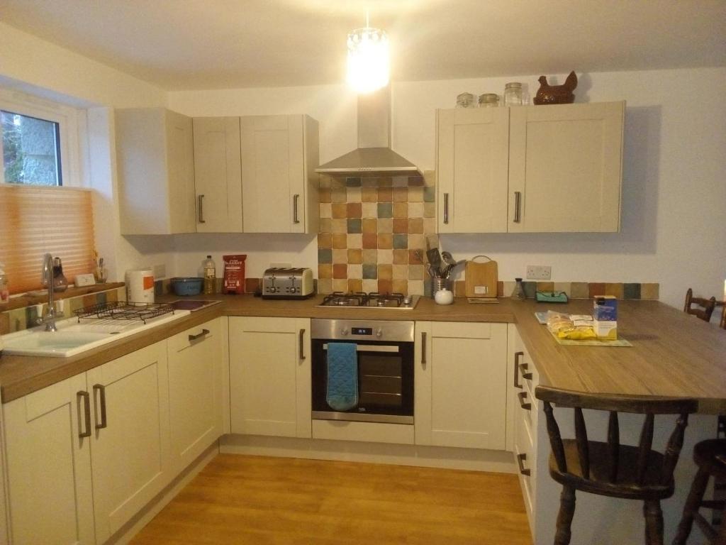 a kitchen with white cabinets and a stove top oven at Sammy's place in Hayle