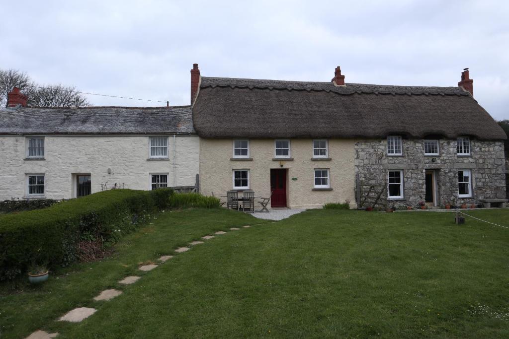 an old stone house with a grassy yard at Cornish Thatched Cottage in Gwennap