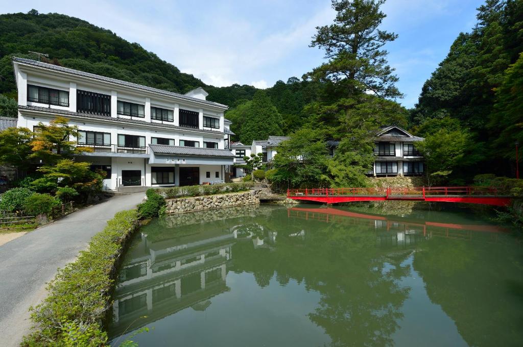 a river in front of a building with a bridge at Yumoto Ueyama Ryokan in Himeji